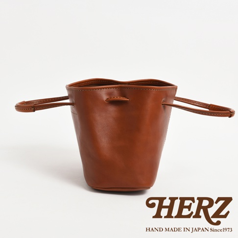 HERZ 職人手作皮革桶包，棕色皮革材質，附有可調式提把，可手提或肩背。