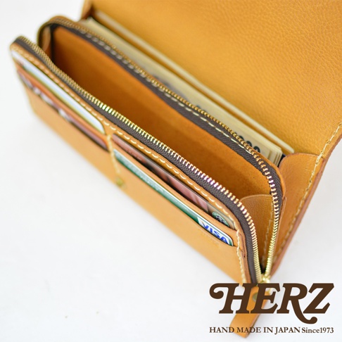 職人手作皮革長夾，淺棕色，拉鍊開合，內部有卡片夾層，可見多張信用卡及紙鈔。