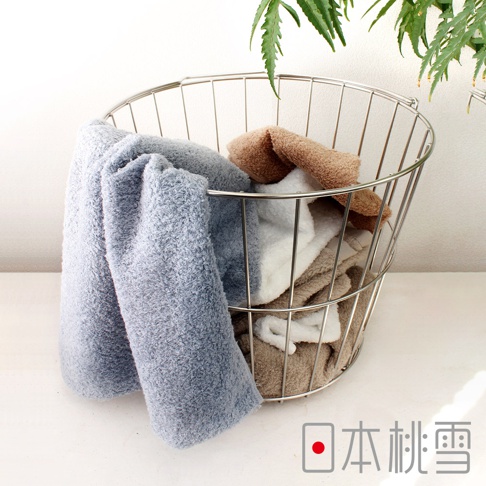 淺藍色、白色、褐色和灰色雙股紗絨毛吸水巾，堆疊在金屬線籃中，部分毛巾垂掛在籃外。