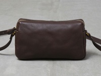 職人手作深棕色皮革輕巧拉鍊單肩包，包身呈長方形，搭配金色拉鍊和金屬扣環，側邊配有可調節的皮革背帶。