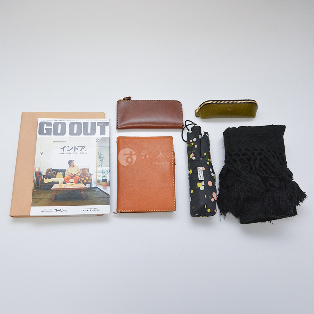 一本雜誌、一個棕色皮革長夾、一個橄欖綠皮革筆袋、一本咖啡色皮革筆記本、一把黑色傘、一條黑色流蘇圍巾。