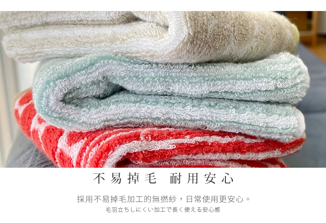 三條顏色不同的毛巾疊放，其中一條是紅色和白色的條紋，上面是淺綠色和白色的毛巾，最上面是白色和米色的毛巾，文字說明不易掉毛、耐用安心。