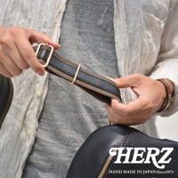 職人手作皮革多功能收納斜背包，黑色皮革包身，搭配咖啡色帆布與黑色皮革拼接的肩帶，肩帶上飾有金色金屬調節環。