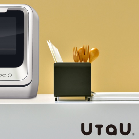 黑色不鏽鋼窄型碗碟瀝水架，附有白色瀝水盤，架內置有木製餐具，背景為黃色。