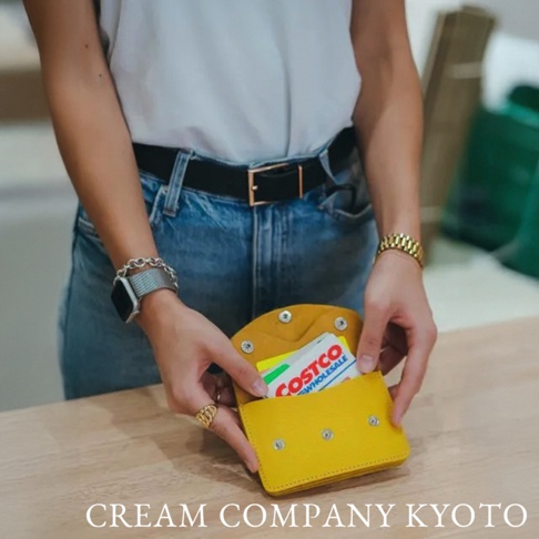 黃色皮革手作零錢包，設有按扣開合，內有卡片，由手持著的女性展示。