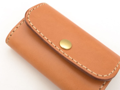 職人手作經典鑰匙包，採用天然皮革材質，呈現溫潤的棕褐色調，搭配金色按扣，車縫線細緻，設計簡潔。