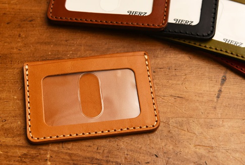 職人手作皮革橫式票券收納夾，採用 tan 色皮革製作，搭配清晰的透明夾層，邊緣有精緻的縫線裝飾。