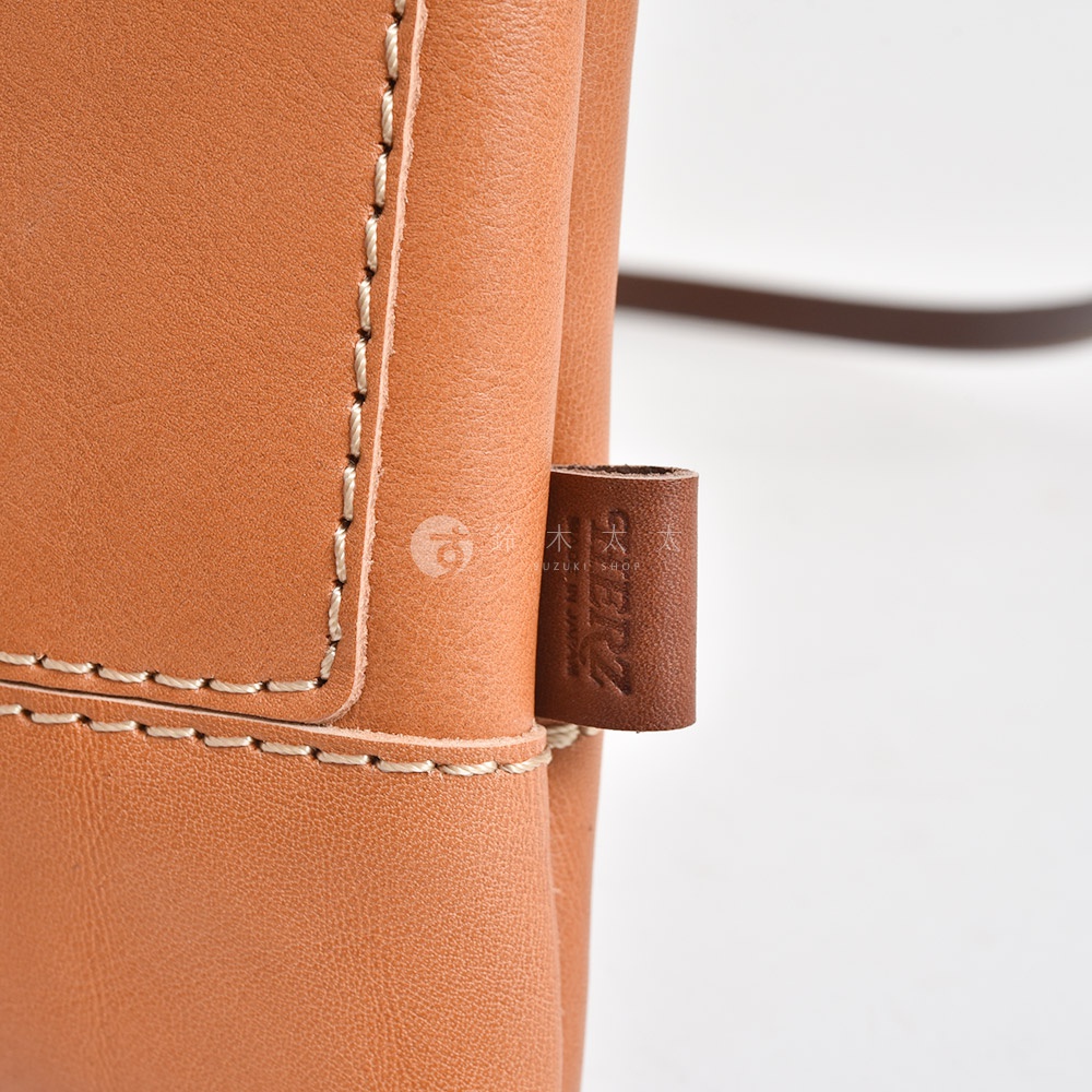 職人手作皮革直式隨身單肩包 CP-37，淺棕色皮革，車縫線清晰，側邊有品牌標籤。