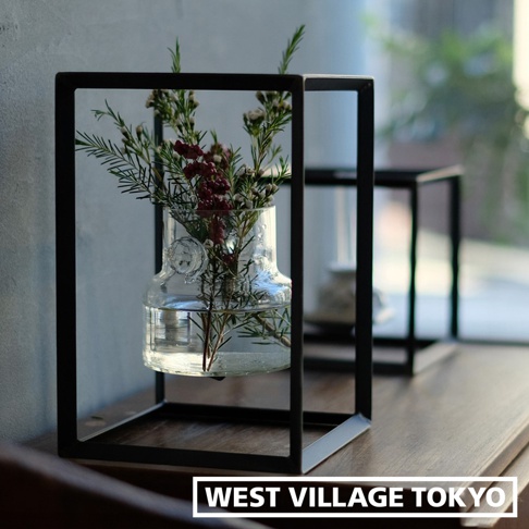 黑色金屬製長方型展示架，內置透明玻璃花瓶，瓶中插有綠葉及深紅色漿果的枝條。