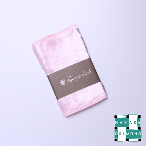 一塊粉紅色、絨毛質地的廚房擦拭布，中間圍繞著印有「Range cloth」字樣和茶壺圖案的咖啡色紙帶，產品底部右側有「HARADA ORIMONO」的綠色與白色標誌。