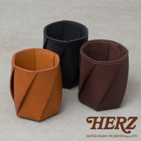 三款職人手作皮革Organ六角收納筆筒，包括淺棕色、黑色和深棕色，以扭轉的皮革設計呈現，用於桌面收納。