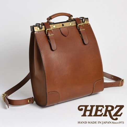 棕色皮革復古口金後背包，配有金屬扣環和可調節的皮革肩帶，頂部設有提把，展現職人手作質感。