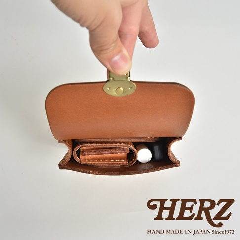 一個打開的棕色皮革腰包，內部裝有錢包和化妝品。包包採用經典設計，配有黃銅鎖扣。