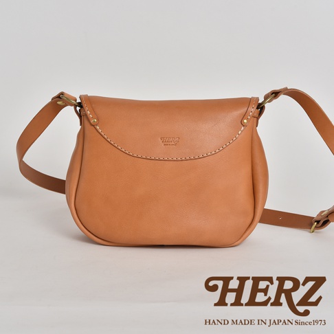 日本HERZ 職人手作皮革休閒旅行馬鞍包，以淺褐色Stare皮革製成，簡潔的設計上有品牌壓印Logo，寬27x高20x厚度8cm，附可調式長肩帶，日本製造
