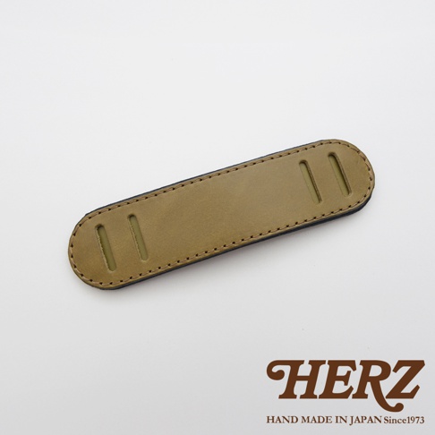 職人手作皮革肩墊，呈現大地色系皮革表面，搭配深色縫線與兩側長形開口，適合搭配各式包款。