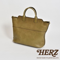 一咖橄欖綠皮革兩用托特包，具有圓潤提把和簡潔線條，包身前方有兩條水平縫線裝飾，材質呈現自然皮革紋理。