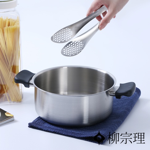 霧面不鏽鋼雙耳鍋，鍋身呈現銀灰色，配有黑色把手，鍋內放有濾網夾，鍋旁有裝滿義大利麵的玻璃罐。