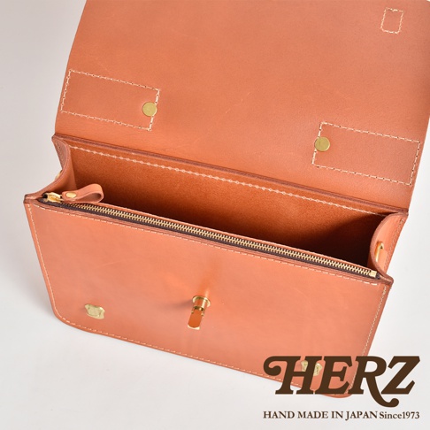 職人手作皮革經典三扣兩用商務公事包，以天然皮革製成，呈現溫潤的橘棕色調。包款設計簡約，採用金屬壓扣及拉鍊開合，內部分層清晰，適合商務使用。