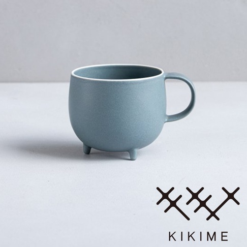 一個藍灰色的美濃燒馬克杯，帶有圓潤的球形杯身和三個支腳。杯口內緣有白色飾邊，杯身表面呈現霧面質感。