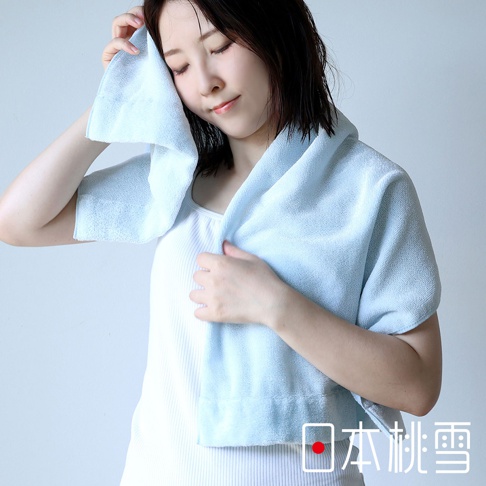 一位女性使用淺藍色厚手迷你浴巾擦拭臉部，浴巾材質柔軟，有清晰的織紋，整體呈現清爽感。
