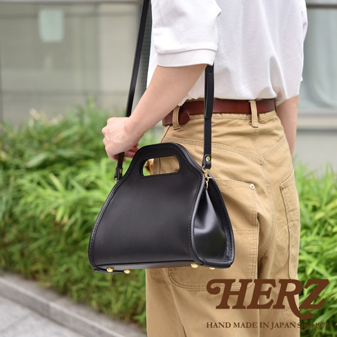 黑色皮革單肩兩用拱型手袋，配有手柄和可拆卸肩帶，金屬扣細節。