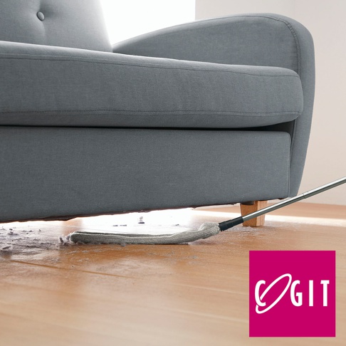 灰色布藝沙發底部，伸縮式清潔刷的灰色布頭正在清潔木質地板上的灰塵和毛髮。