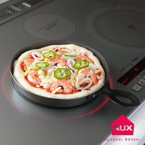 leye 披薩小鐵鍋，圓形金屬鍋身，內含未烘烤的披薩，配料有蝦仁、魷魚圈、甜椒圈及起司，放置於電磁爐上，鍋邊散發紅色熱力。