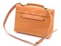 職人手作的棕色皮革雙扣三用後背包，包身線條簡潔，前方有方形口袋設計，搭配金屬扣環與可調節的皮革背帶，展現經典質感。