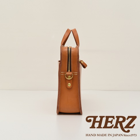 職人手作皮革兩用商務公事包，側邊視角，展示淺棕色皮革材質、拉鍊開合、金屬五金配件及提把。