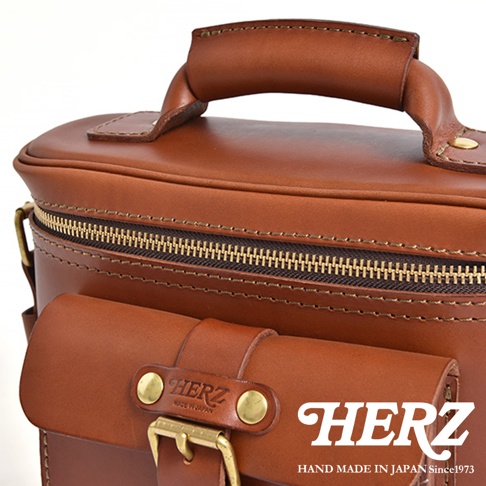 日本HERZ手工皮革相機包，近距離特寫，展現其精緻的縫線、黃銅拉鍊和標誌。