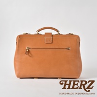 一咖淺棕色皮革製成的三用背包，具有經典的醫生包造型，正面有一個拉鍊口袋，背包頂部有提把和金屬扣，整體以縫線裝飾，底部有金屬腳釘。