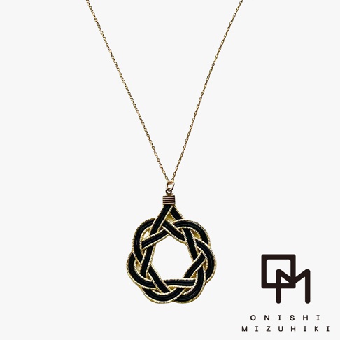 一條細緻的金屬鍊子，垂掛著一個以黑色和金色線條編織而成的圓形水引花結墜飾，墜飾中央簍空，呈現出精緻的日式傳統手工藝風格。