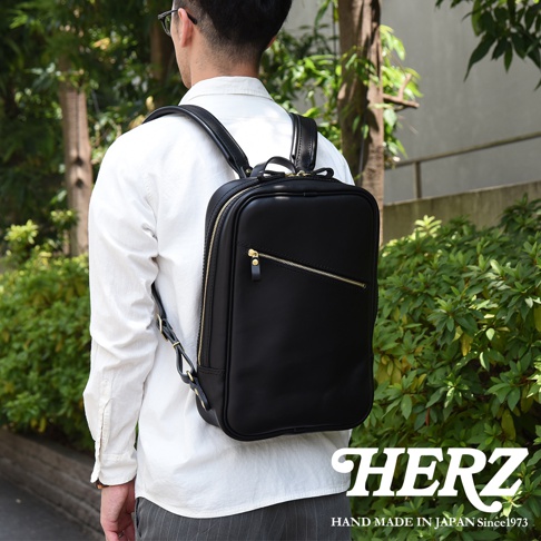 職人手作黑色皮革長方型多口袋後背包，配有金色拉鍊和品牌標誌。