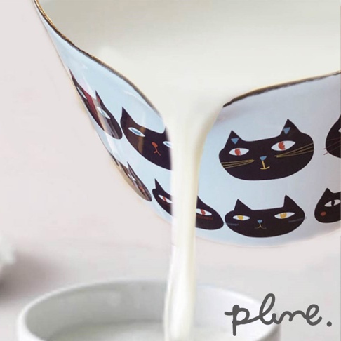 琺瑯單柄牛奶鍋，淺藍色鍋身飾有黑色貓臉圖案，金屬邊緣。