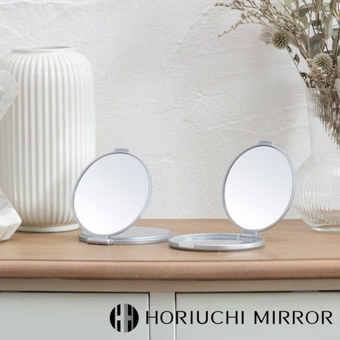 堀內鏡 HORIUCHI MIRROR 隨身口袋3倍放大小圓鏡，銀色鏡框，立於木質桌面。