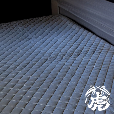 單人竹炭床墊，深灰色，菱格紋縫製，鋪設於床架上。