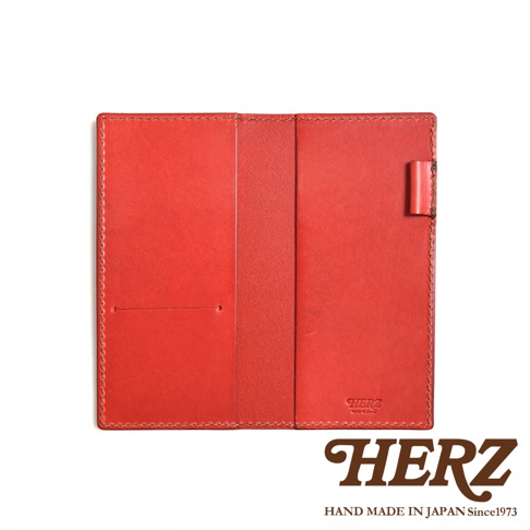 紅色皮革製成的輕便記事本書套，內有兩個卡槽，外側有皮革固定帶，邊緣縫線整齊，左下方印有「HERZ」品牌標誌。