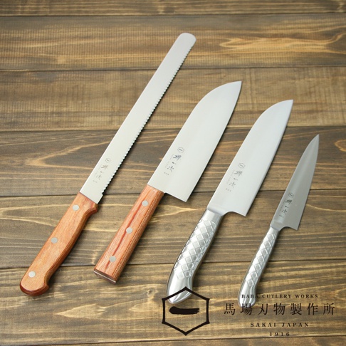四把不鏽鋼廚房刀具，包括一把長鋸齒刀和三把光滑刀刃的刀。其中兩把刀有木製刀柄，另外兩把刀有銀色金屬刀柄，刀柄上帶有菱形紋路。