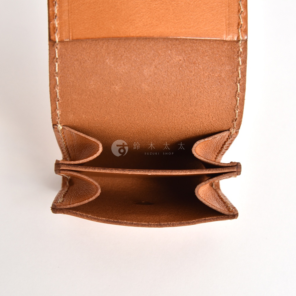 一個日本HERZ職人手作的淺棕色皮革零錢包，呈現由上往下俯視的開啟視角。錢包內部採用摺疊式風琴設計，展示出分層的收納空間與厚實的皮革質感，邊緣處帶有清晰的縫線細節，中央印有鈴木太太的品牌標誌。