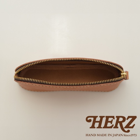 職人手作皮革三角弧形收納筆袋，淺棕色皮革，拉鍊為金色，內部為同色皮革，整體呈現簡約弧形設計。