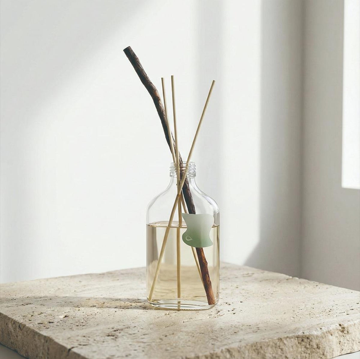 裝有香氛精油和擴香竹的玻璃瓶，瓶身貼有綠色裝飾。