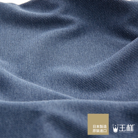 藍色織紋枕套，材質細緻，帶有細小的網狀紋理，布料表面平整，部分區域有自然的皺褶，左下角有品牌標誌與日文說明。