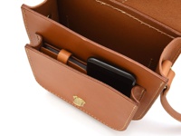棕色皮革製成的單肩包，包蓋開啟，露出內部結構，可見手機放置於前袋。