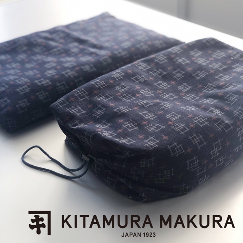 深藍色織物枕，帶有白色和淺棕色格子圖案。其中一個枕頭有抽繩閉合，另一個枕頭平放。