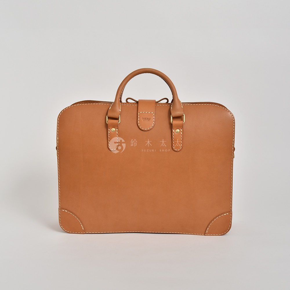 職人手作皮革三層收納兩用商務公事包，淺棕色，設有雙提把，前有皮革束帶開合，包角有加固縫線。