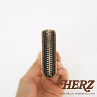 HERZ 品牌標誌，下方有 HAND MADE IN JAPAN Since1973 字樣，中間為一個棕色皮革拉鍊筆袋的側面特寫。
