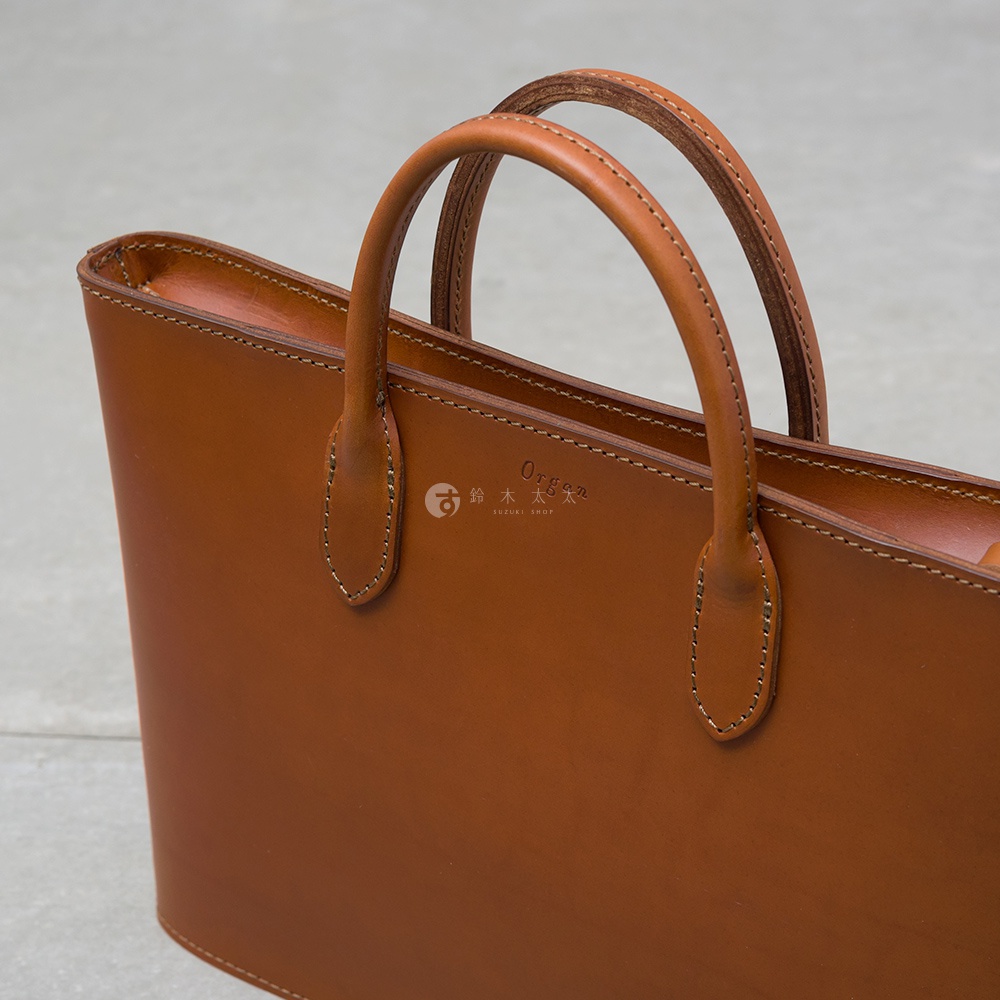 職人手作皮革Organ薄型公事包，經典棕色，採用光滑皮革材質，設有兩條圓弧形提把，包身線條簡潔，縫線精緻。