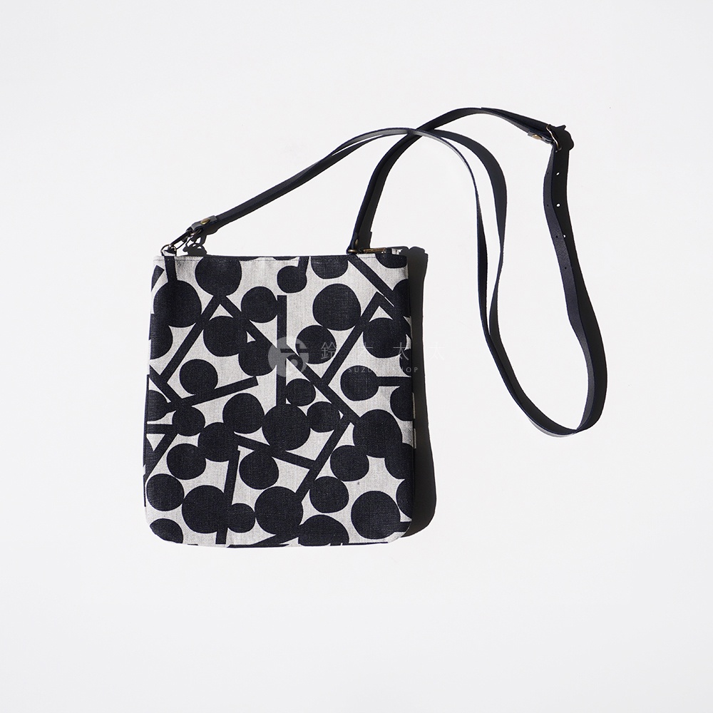 BAN INOUE 自然織紋麻布斜背包，印有黑白幾何圓點與線條圖案，配有黑色皮革揹帶。