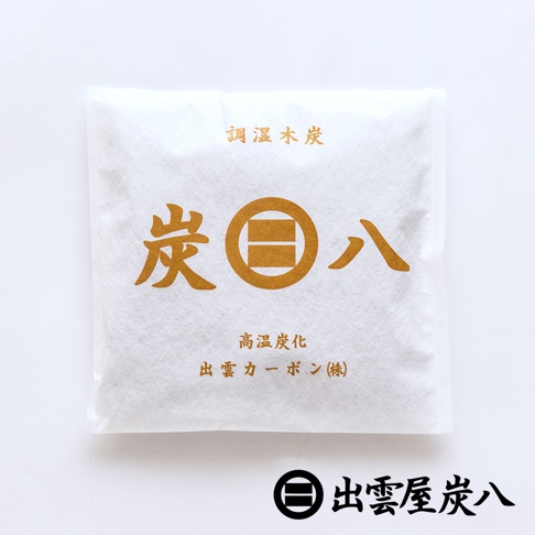 白色正方形包裝袋正中央印有金色的出雲屋炭八品牌標誌與文字，包裝上方標示調濕木炭，下方標註高溫炭化與出雲碳素株式會社字樣，下方並附有品牌標誌與出雲屋炭八黑色字樣，外觀簡約素雅。