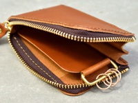 淺棕色皮革製作的拉鍊卡片鑰匙包，展示其開放的內部結構，內有卡槽和一個帶有銅色鑰匙圈的皮革環。